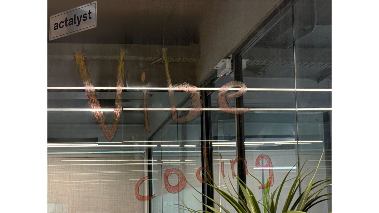 Actalyst office glass wall with the words "vibe coding" written across it.